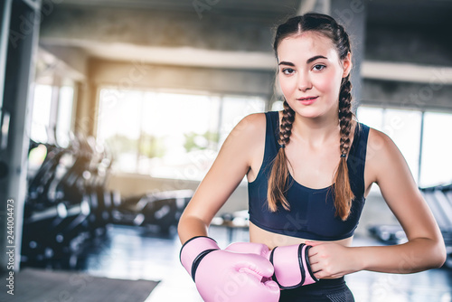Attractive young Caucasian woman in boxing gloves. fashionable studio portrait of an sporty lady at gym background 