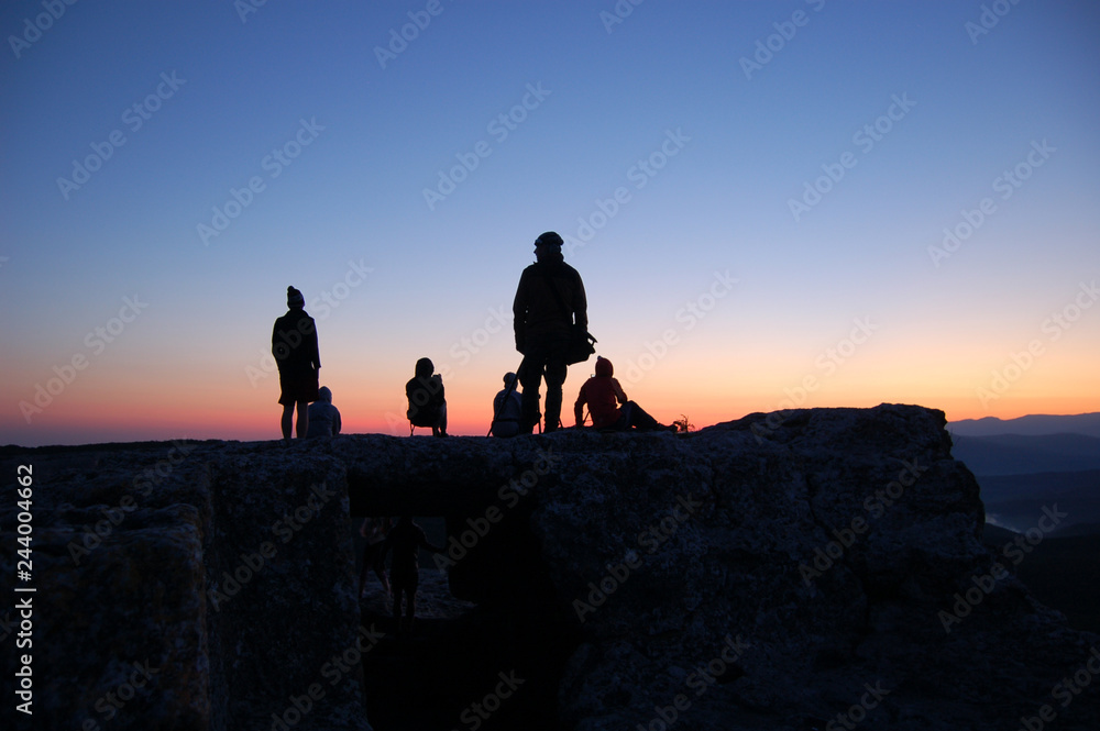 Tourists watch sunrise of the sun on the mountain of Mangup in the Crimea