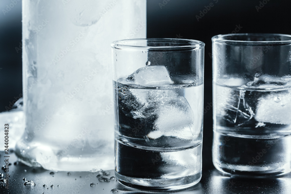 Cold vodka in shot glasses on a black background. Cold vodka in shot glasses on a black background.