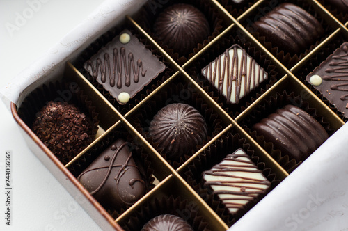 Assortment of Chocolates in box (selection focus). Close up assortment of chocolate candies in box. Collection of tasty candies in box, top view. Dessert for gourmet. Sweet gift on Valentines Day.