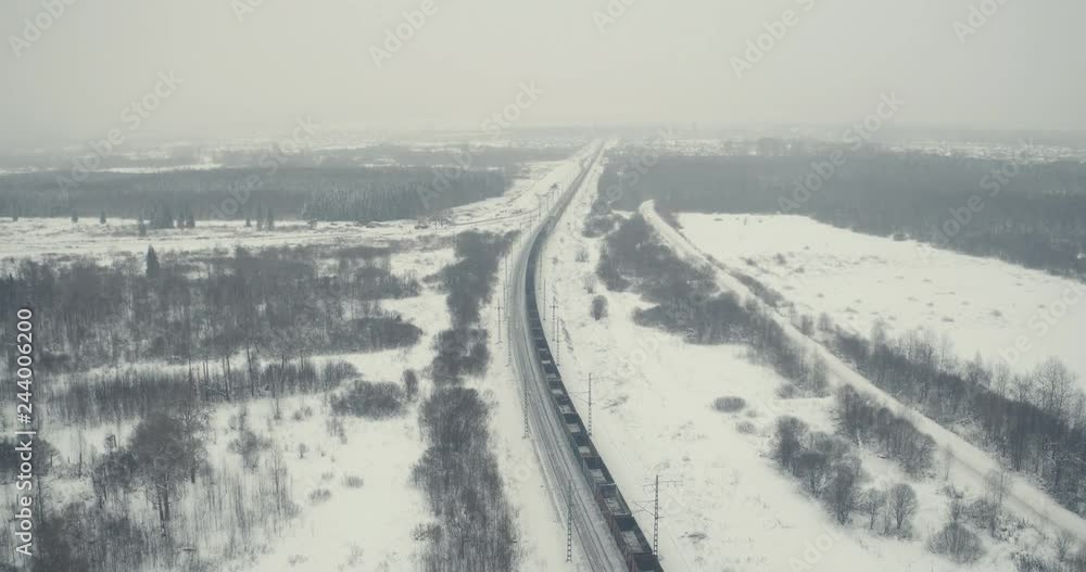 Freight train carries with coal an electric locomotive by Trans Siberian railway in winter cloudy frozen day - Aerial View Freight train carries with coal an electric locomotive by Trans Siberian railway in winter cloudy frozen day - Aerial View