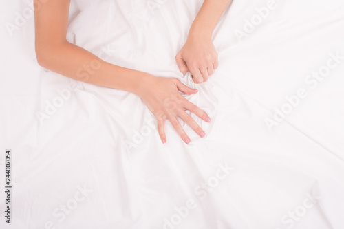 Female hands crumple white sheet, woman making sex, focus on hands