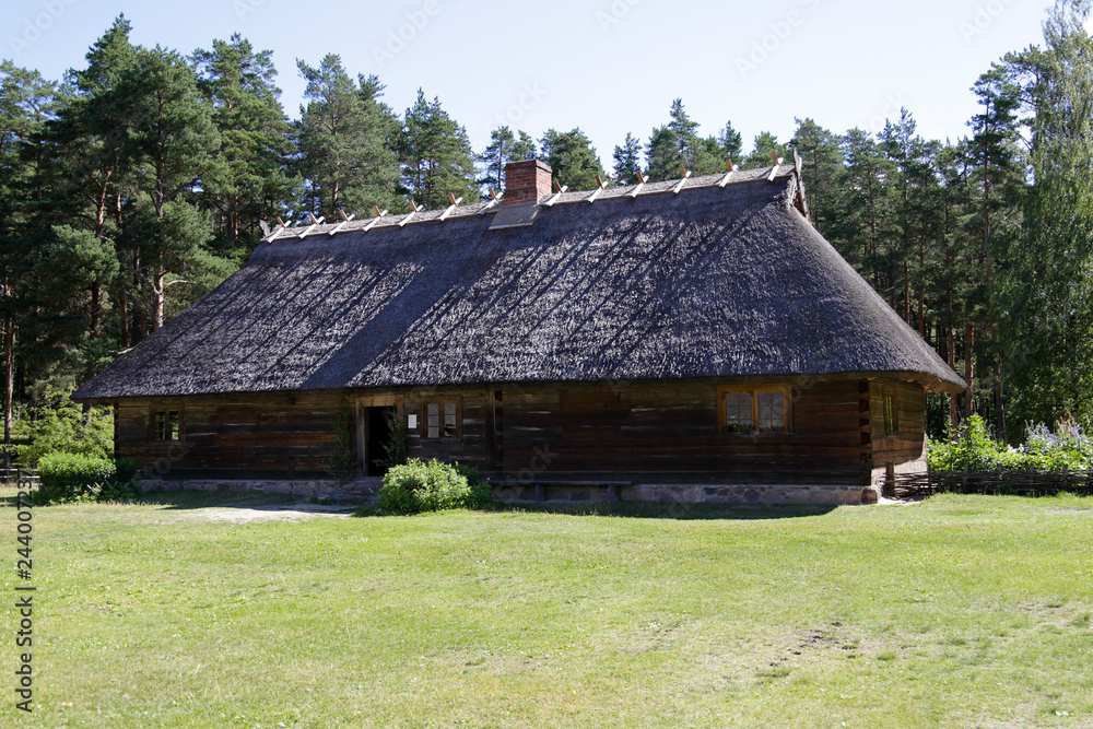 Traditional old wooden house with reed roof in Latvia Traditional old wooden house with reed roof in Latvia