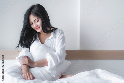 Beautiful young pretty Asian woman wake up and make happy smile with white shirt at the white bed in the morning.   © totojang1977