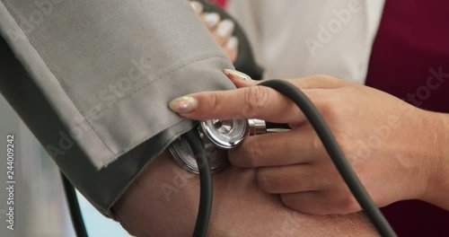 Extreme close up on doctor using sphygmomanometer to check blood pressure