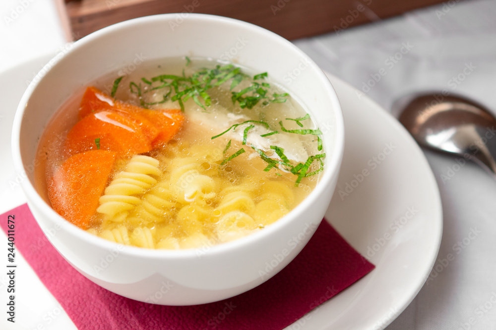 Chicken soup with pasta fusilli in the bowl on the wood table Chicken soup with pasta fusilli in the bowl on the wood table