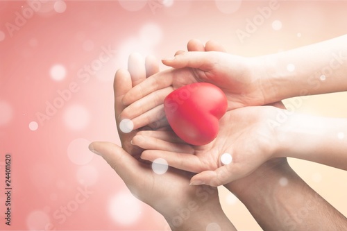 Adult and child hands holding red heart