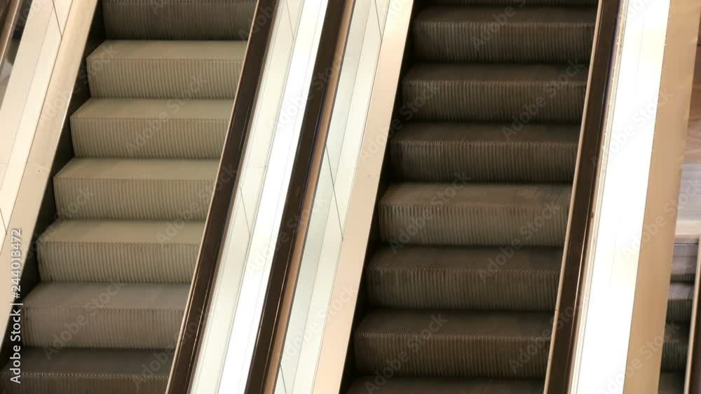 Two escalators in shopping centre which move up one another down close up view. Two escalators in shopping centre which move up one another down close up view.