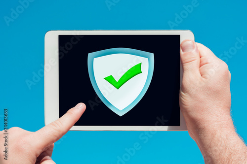 Man holding a tablet device pointing at an anti-spam, security firewall icon