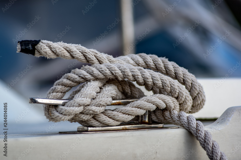 Close up view of white rope tied around ship bollard.