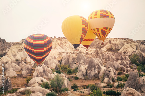 Hot air balloon flying over Cappadocia mountain landscape at gold sunrise