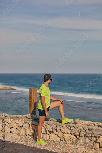 Sportsman stretching on a tropical exotic cliff near the ocean. © astrosystem