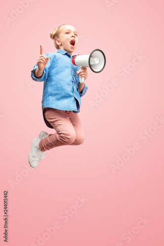 Beautiful young child teen girl jumping with megaphone isolated over pink background. Runnin girl in motion or movement. Human emotions,, facial expressions and advertising concept