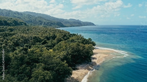aerial drone image of a remote south pacific island with sandy beach shore and beautiful ocean sea seascape and lush tropical rainforest jungle with a reef and river