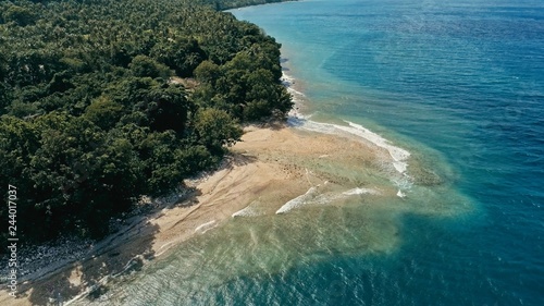 aerial drone image of a remote south pacific island with sandy beach shore and beautiful ocean sea seascape and lush tropical rainforest jungle with a reef and river