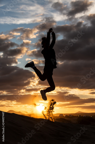 Anonymous person jumping during sunset