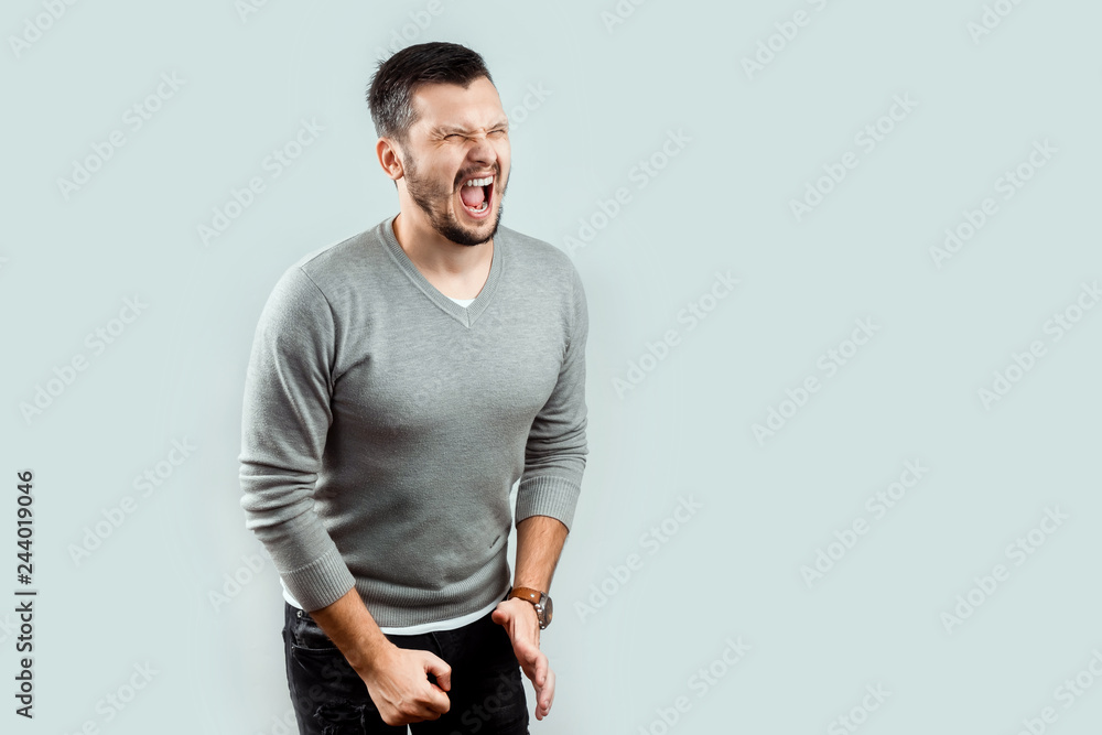 A young, attractive man feels pain in his groin, arms folded between his legs. Experiencing pain, male problems, potency. A young, attractive man feels pain in his groin, arms folded between his legs. Experiencing pain, male problems, potency.