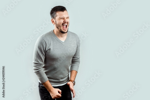 A young, attractive man feels pain in his groin, arms folded between his legs. Experiencing pain, male problems, potency.