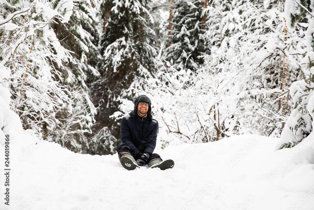 Man in fur winter hat with ear flaps smiling portrait. Extreme in the forest