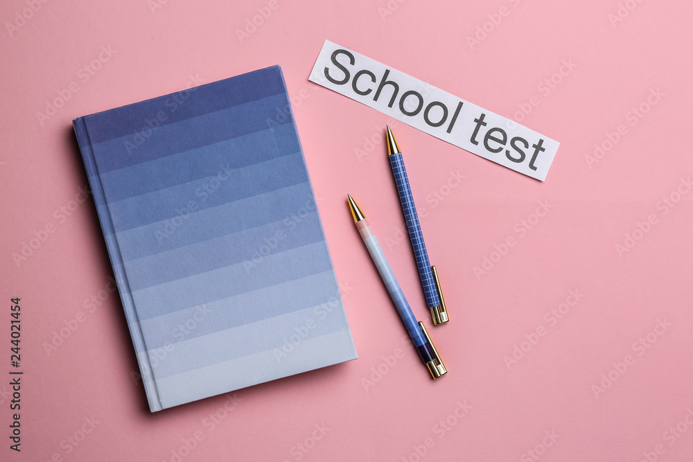 Notebook, pens and paper with text SCHOOL TEST on color background Notebook, pens and paper with text SCHOOL TEST on color background