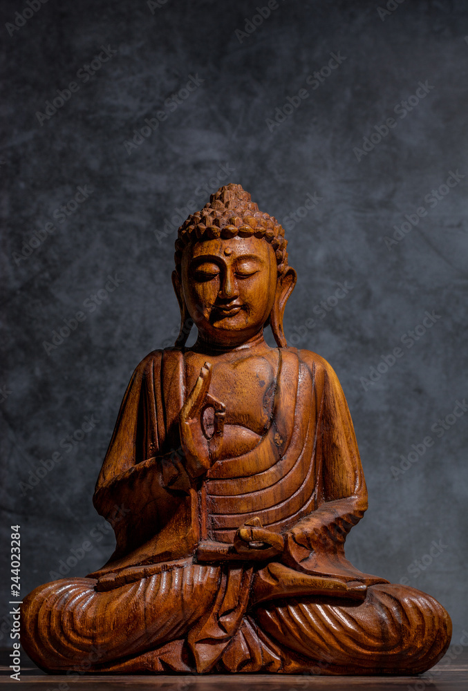 Wooden made buddha on a grey stone background