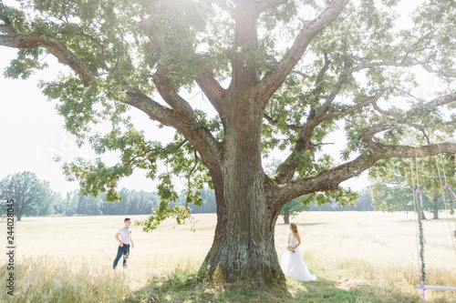 bride and groom look at each other between them tree