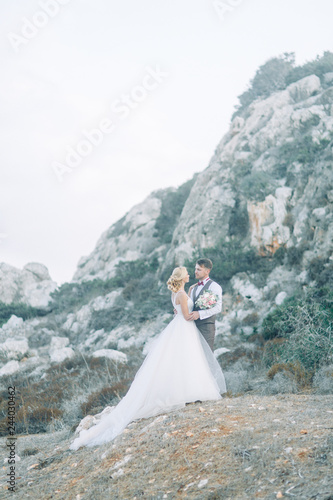 Wedding couple in the mountains at sunset in Cyprus. Beautiful panoramic view and the happy couple.