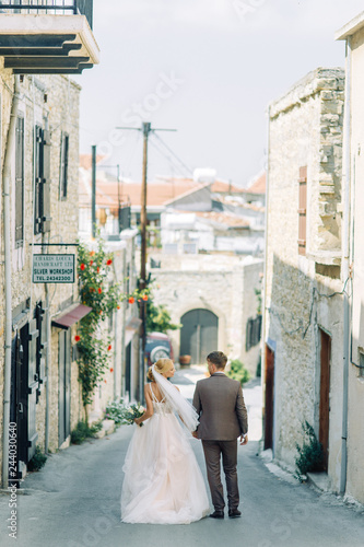 Wedding on the city streets of Cyprus. Beautiful couple walking and laughing, the architecture of the city. © pavelvozmischev