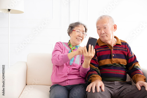 happy senior couple looking at mobile phone