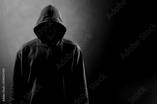 Dark unrecognisable man in hoodie on background