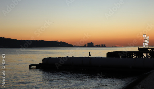 Man walking in a jetty with a river in background at the sunset. Lisbon Portugal