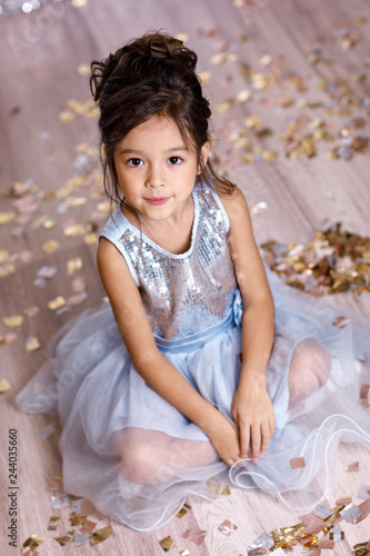 little girl in blue dress sitting on the floor with confetti