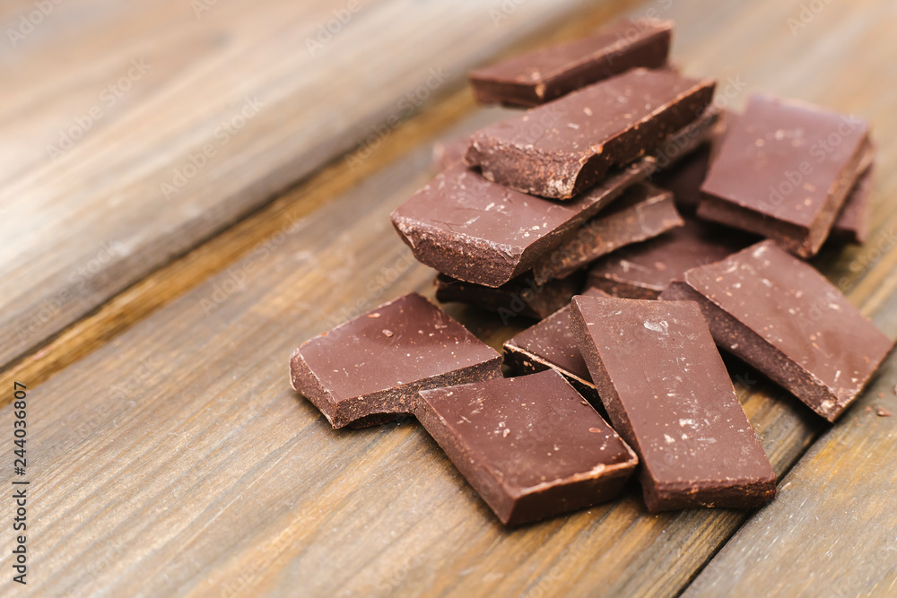 Dark chocolate is lying on a wooden background. Soft focus Dark chocolate is lying on a wooden background. Soft focus
