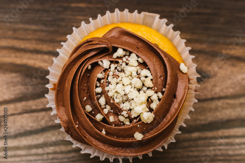 Chocolate muffin sprinkled with nut crumbs on a wooden background. Top view