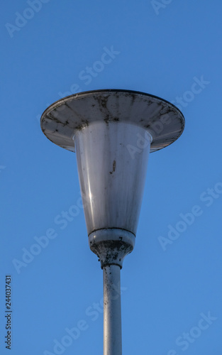 Dirty street lamp against the blue sky in the afternoon