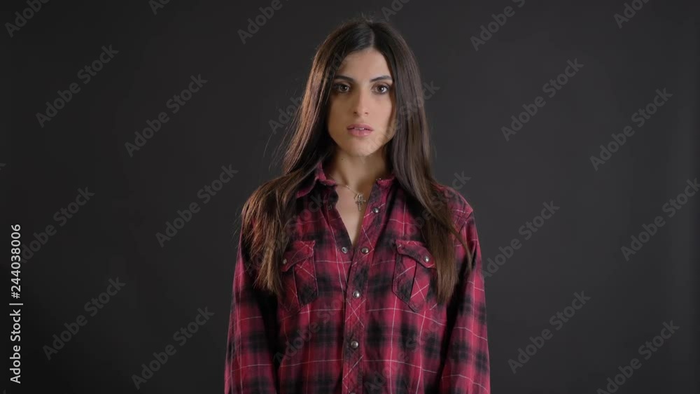Portrait of caucasian long-haired brunette girl seriously watching into camera on black background. Portrait of caucasian long-haired brunette girl seriously watching into camera on black background.
