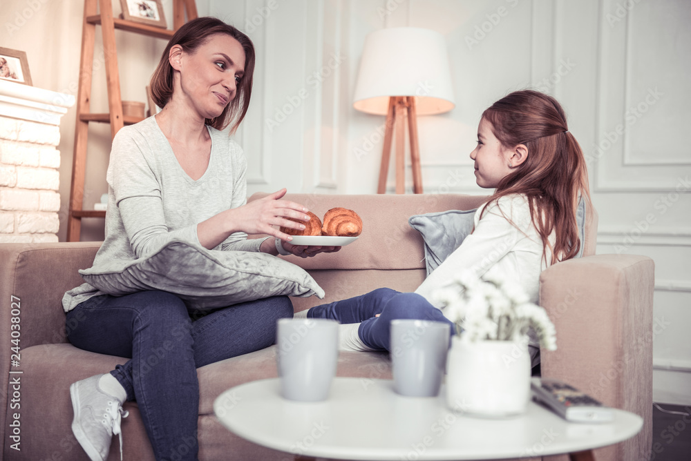 Pleasant nice woman holding a plate with croissants Pleasant nice woman holding a plate with croissants