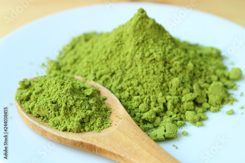 Closed Up a Spoon of Vibrant Green Matcha Tea Powder on a Plate with Blurry Green Tea Powder Pile in Background 
