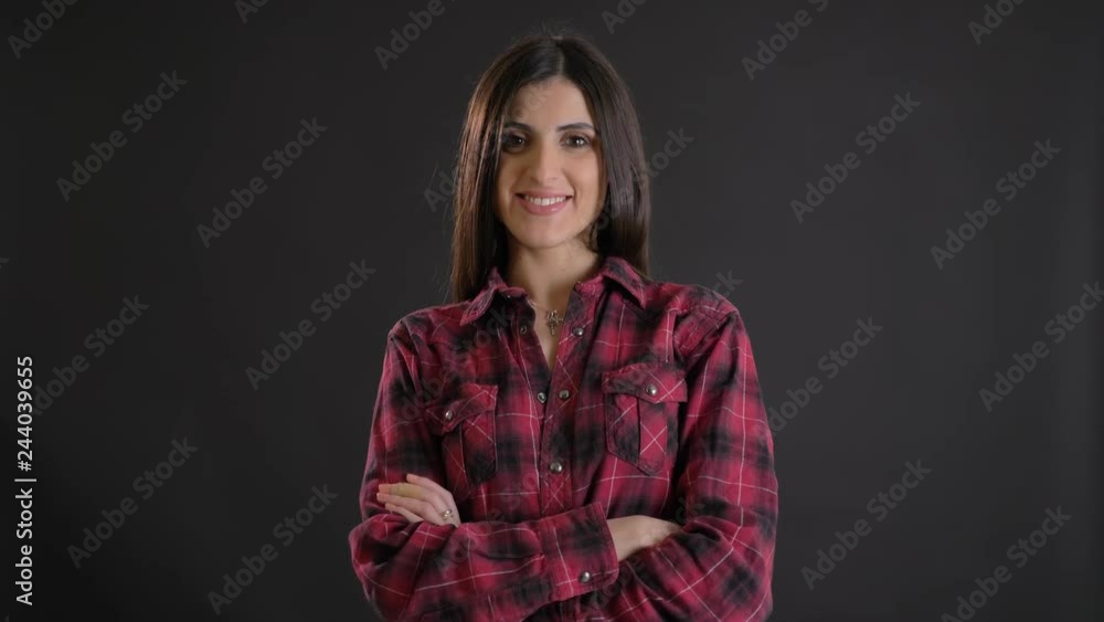Portrait of caucasian long-haired brunette girl with arms crossed shyly smiling into camera on black background. Portrait of caucasian long-haired brunette girl with arms crossed shyly smiling into camera on black background.