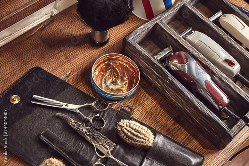 Hairdresser tools on wooden background. Top view on wooden table with scissors, comb, hairbrushes and hairclips, trimmer.