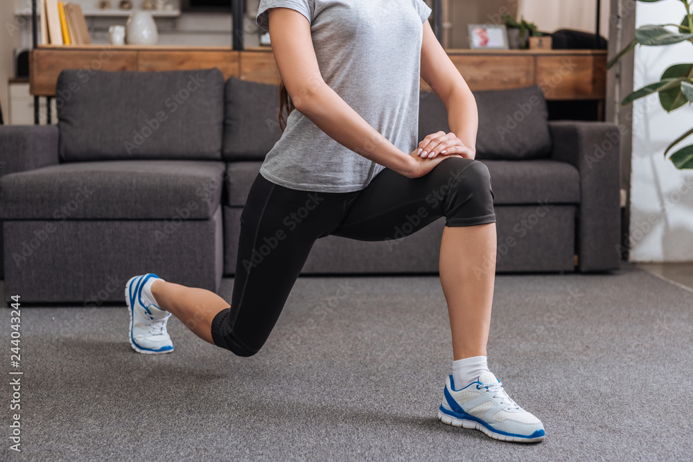 cropped view of sportswoman doing lunge exercise at home cropped view of sportswoman doing lunge exercise at home