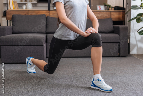 cropped view of sportswoman doing lunge exercise at home