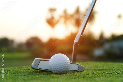 Golf ball and golf club in beautiful golf course at sunset background.