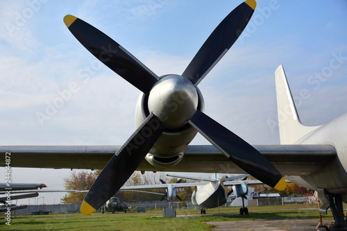 Retro plane with propellers on blue sky background. Airplane details with clouds. Aviation transport on airfield. Black propeller blade with yellow on the top. Jet engine of an vintage airliner.