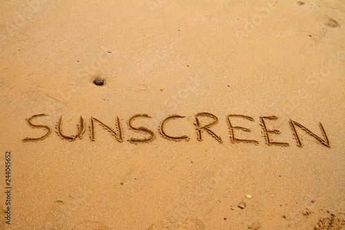 The word sunscreen drawn in sand at the beach