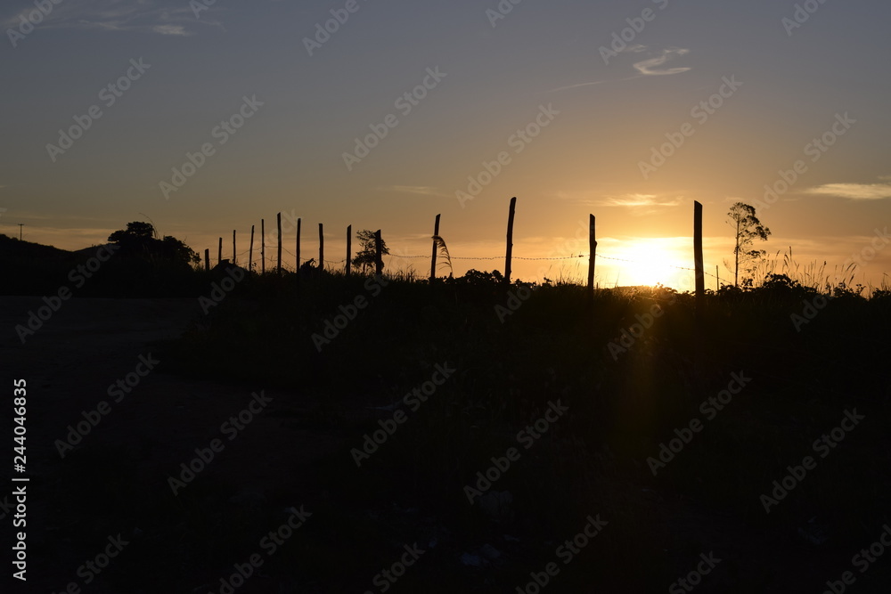 Fototapeta premium Horizonte plano e pôr-do-sol, cerca de madeira, paisagem rural
