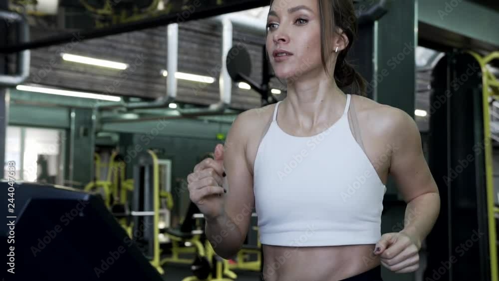 Close-up - A Beautiful Young Female Fitnes Model Is Running On A Treadmill In The Gym. Healthy Lifestyle Concept. Close-up - A Beautiful Young Female Fitnes Model Is Running On A Treadmill In The Gym. Healthy Lifestyle Concept.