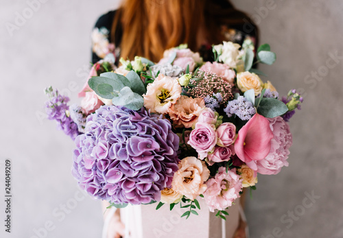 Wallpaper Mural Very nice young woman holding beautiful blossoming bouquet of fresh hydrangea, calla lilies, roses, eustoma, carnations, eucalyptus, mattiola flowers in purple color on the grey wall background  Torontodigital.ca