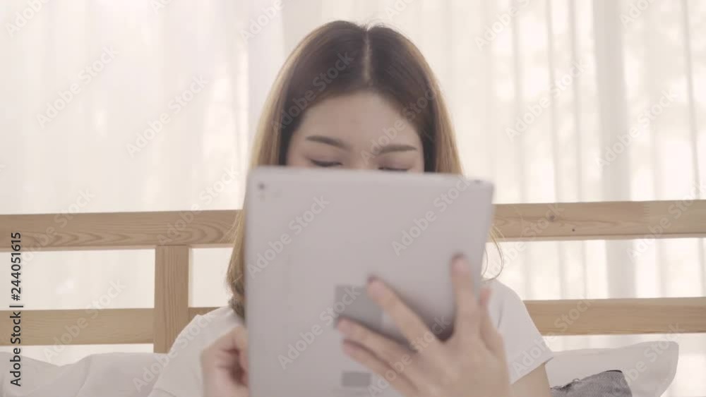 Young Asian woman using tablet while lying on bed after wake up in the morning, Beautiful attractive Japanese girl smiling relax in bedroom at home. Enjoying time lifestyle women at home concept. Young Asian woman using tablet while lying on bed after wake up in the morning, Beautiful attractive Japanese girl smiling relax in bedroom at home. Enjoying time lifestyle women at home concept.