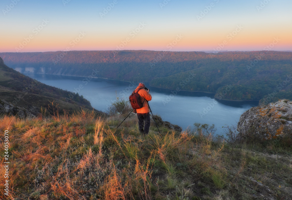 Fototapeta premium the photographer shoots the canyon of the picturesque river. tourist on the rock. autumn morning 